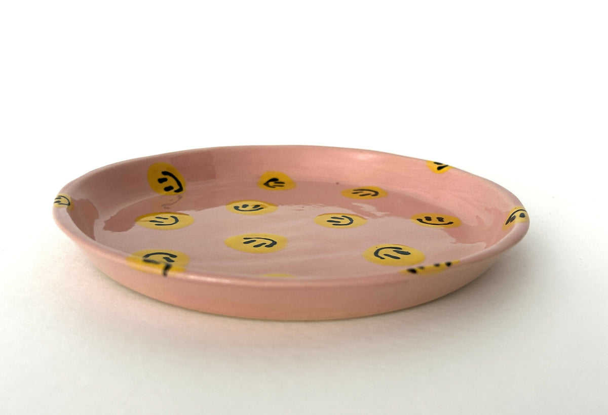 Handmade ceramic plate with pink background and yellow smileys