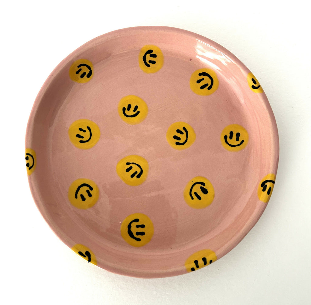 Handmade ceramic plate with pink background and yellow smileys